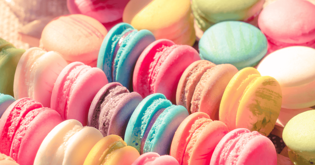 Colorful assortment of macarons in pastel pink, blue, yellow, green, and purple shades arranged in neat rows, creating a vibrant and appetizing display of the delicate French cookies—perfect for indulging your sweet tooth without a hint of food guilt.